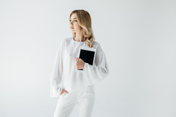 young attractive woman in white clothing with tablet posing isolated on grey - Foto, imagen