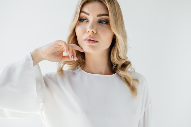 portrait of pensive blond woman in white clothing posing on white backdrop - Photo, Image