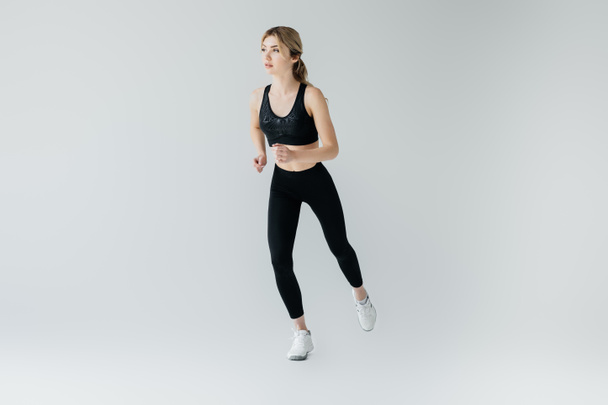 young athletic sportswoman exercising isolated on grey - Photo, Image