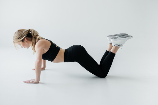 boční pohled na mladé sportovkyně dělá push ups izolované Grey - Fotografie, Obrázek