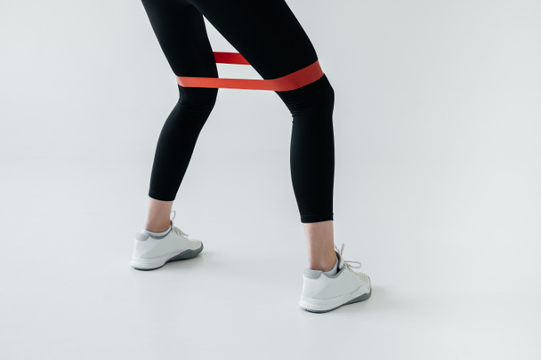 partial view of exercising with rubber tape on grey background - Foto, imagen