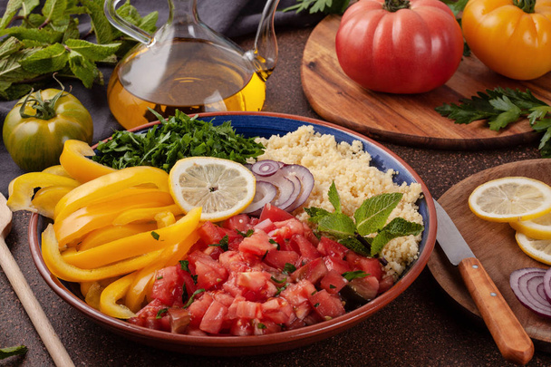 Ingredientes frescos para la ensalada tabbouleh: cuscús, tomates, limón, perejil, menta, aceite de oliva, pimiento. Concepto de comida halal saludable y vegetariana
 - Foto, imagen