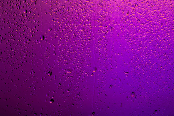Ventana de lluvia. Gotas en el vidrio en la luz trasera púrpura
 - Foto, imagen