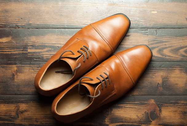 Pair of stylish leather men's shoes on a wooden floor - Фото, изображение