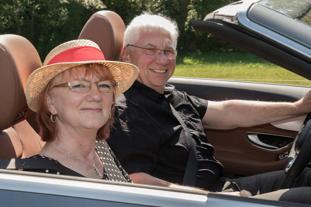 Усміхнена щаслива старша пара в розкішному кабріолеті
 - Фото, зображення