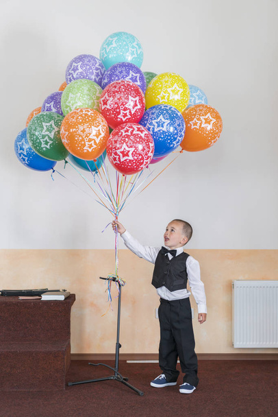 Menino 4 anos segurando balões coloridos. Menino feliz no palco segurando balões
. - Foto, Imagem