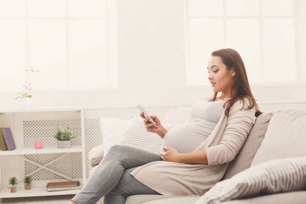 Heureuse femme enceinte utilisant un smartphone
 - Photo, image