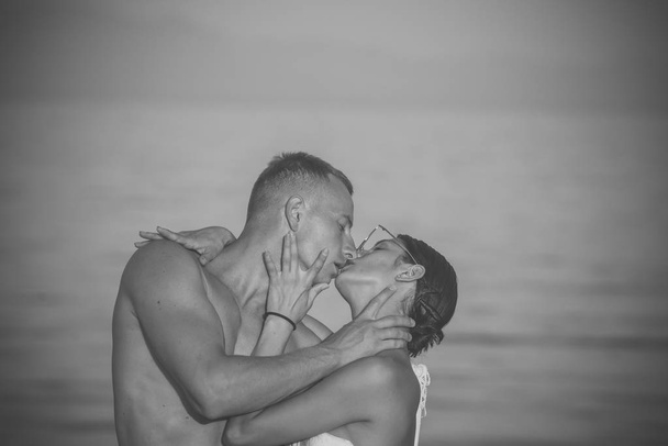 Passionate couple kissing, boy and girl. Passionate couple kissing on beach, sea water on background, copyspace. Honeymoon and vacation concept. Couple in love relaxing on holiday, honeymoon. Young - Photo, Image