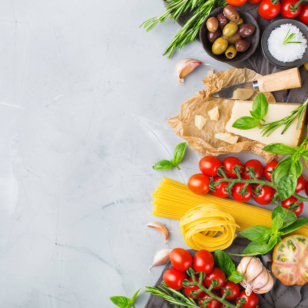 Italian food ingredients cooking background with pasta, olive oil, parmesan cheese, green basil, ripe tomatoes, garlic, herbs. Copy space flat lay top view background - Photo, Image