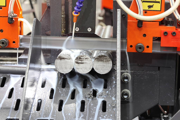 Coupe de barre en acier par scie à ruban avec liquide de refroidissement
 - Photo, image