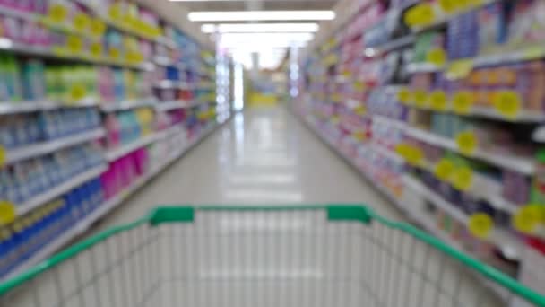 Wazige video van kar van de lege supermarkt vooruit in petto voor kopen sommige goederen en producten op de linker- en rechterhand plank. - Video