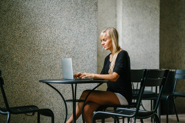 Muotokuva nuori ja houkutteleva vaalea liiketoiminnan nainen työskentelee hänen kannettavan tietokoneen kahvilassa päivällä. Hän istuu alas ja hymyilee keskittyessään työhönsä.
. - Valokuva, kuva