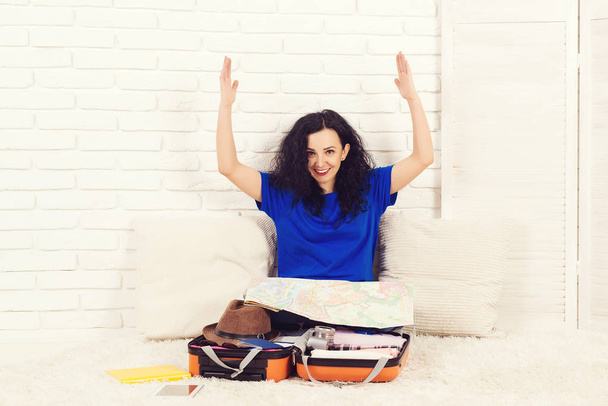 Happy brunete woman is packing a suitcase at home. - Photo, Image