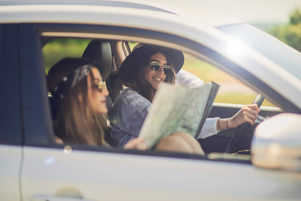 Deux filles qui s'amusent à conduire. Une fille au volant et une autre lisant la carte
. - Photo, image