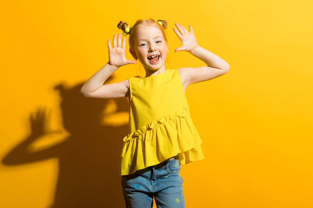 Retrato de uma menina bonita em uma blusa amarela e jeans azul
. - Foto, Imagem