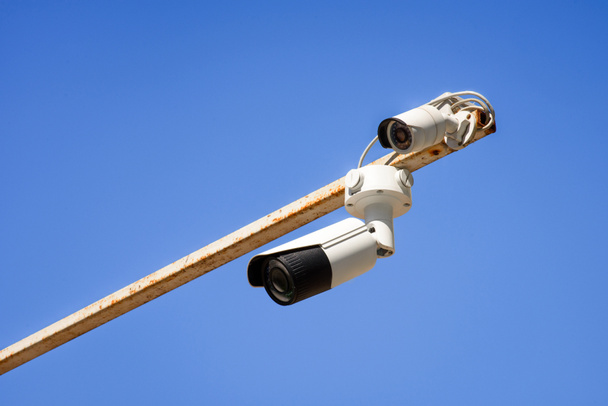 close up view of security cameras on pole against bright blue sky - Photo, Image