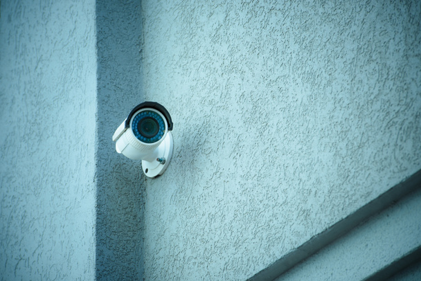 vista de cerca de la cámara de seguridad en la fachada del edificio gris
 - Foto, Imagen