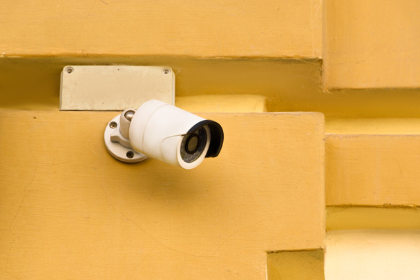 Nahaufnahme von Überwachungskamera an gelber Hausfassade - Foto, Bild