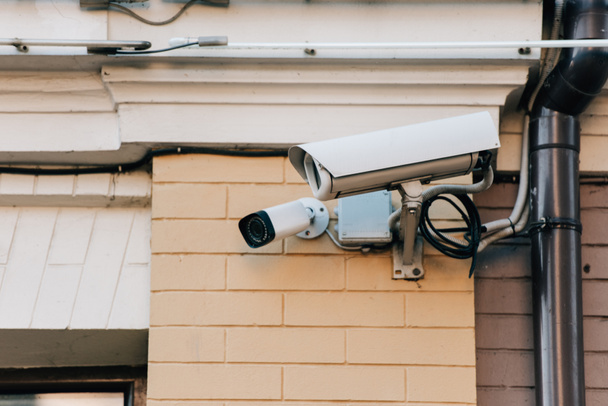 Nahaufnahme von Überwachungskameras an orangefarbener Hausfassade - Foto, Bild