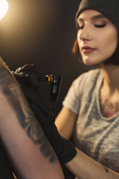 Young woman tattooist doing tattoo on shoulder - Photo, Image