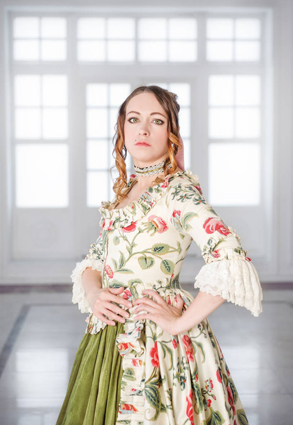 Όμορφη γυναίκα σε μακρύ πράσινο μεσαιωνικό φόρεμα στην αίθουσα - Φωτογραφία, εικόνα