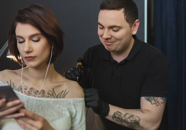 Kobieta, słuchanie muzyki, robiąc tatuaż - Zdjęcie, obraz
