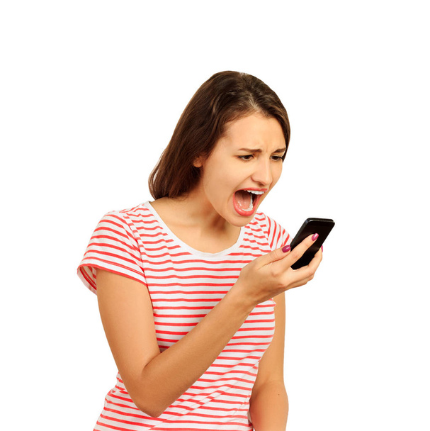 Geërgerd hysterische jonge vrouw schreeuwt in mobiele telefoon, het meisje is ontevreden over het gesprek. emotionele meisje geïsoleerd op witte achtergrond. - Foto, afbeelding