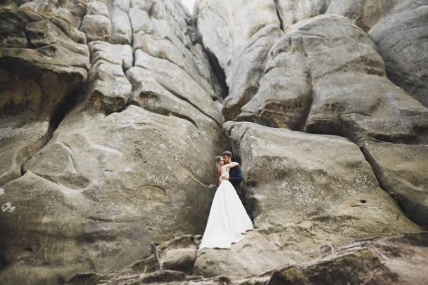 Wedding couple in love kissing and hugging near rocks on beautiful landscape - Photo, Image