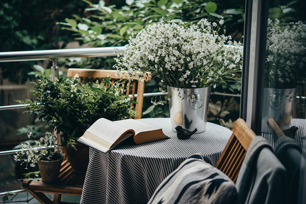 Small table, book and flowers on a beautiful terrace or balcony - Foto, imagen