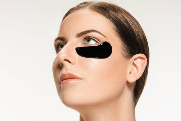 Молодая красивая женщина надевает маску на лицо терапевтической черной грязи. Лечение
 - Фото, изображение