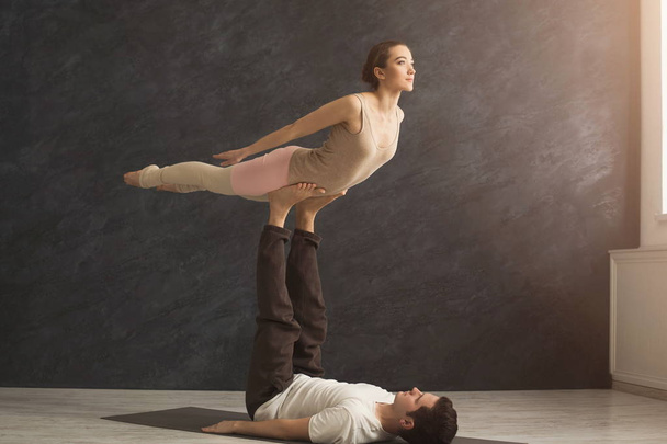 Young couple practicing acroyoga on mat together - Photo, Image