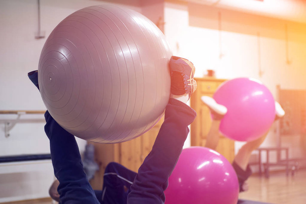oefenen met personal trainer op grote stabiliteit bal in studio fitness terug fysiotherapie - Foto, afbeelding