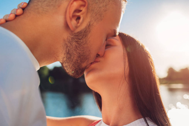 Happy couple in love hugging and kissing by the river at sunset. Romantic date of young hipsters. Closeup - Fotoğraf, Görsel