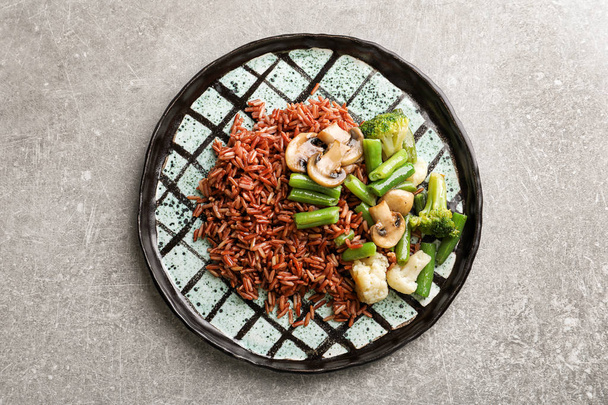 Plate with delicious brown rice and vegetables on light background - Fotografie, Obrázek