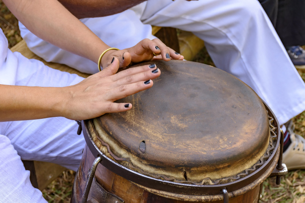 Jonge vrouw percussionist handen spelen een trommel genaamd atabaque tijdens de uitvoering van de Braziliaanse volksmuziek  - Foto, afbeelding