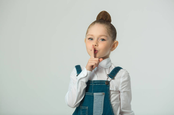 beautiful little girl on a light background with a gesture of hands - Фото, зображення