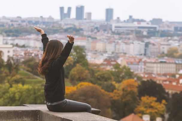 Woman raises up arms in the air and looks at the city from above - Zdjęcie, obraz