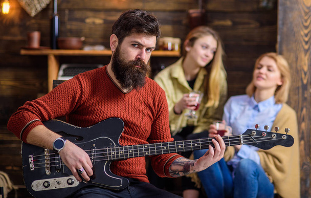 Guitarist rehearsing new show. Bearded man entertaining his wife and daughter with lovely tunes. Rock musician on vacation with family in countryside. Man with stylish hipster beard playing guitar - Фото, зображення