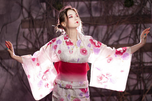 elegant girl in a classic traditional dress Japanese kimono white and pink standing alone on dark background in the studio - Photo, Image
