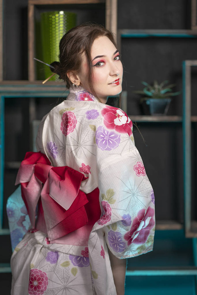 schöne junge Frau, die nachts in ihrem Zimmer steht und allein im japanischen Kimono posiert - Foto, Bild