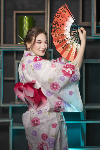 schöne junge Frau, die nachts in ihrem Zimmer steht und allein im japanischen Kimono posiert - Foto, Bild
