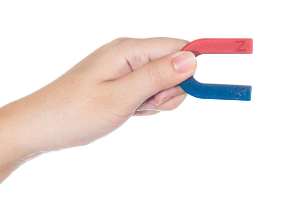 Vrouwelijke hand hebt rode en blauwe magneet geïsoleerd op witte achtergrond - Foto, afbeelding