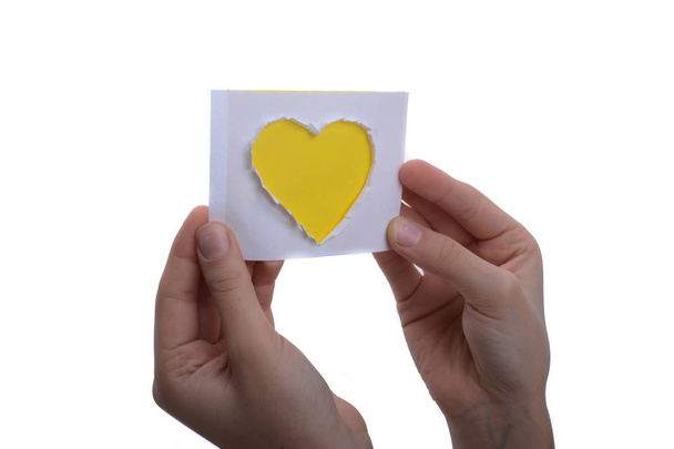 Ręka trzymająca żółty papier w kształcie serca wycięty z papieru na białym tle - Zdjęcie, obraz
