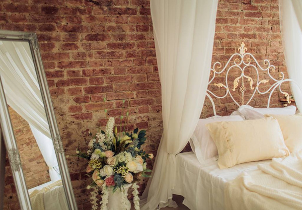 Лофт спальня с белой стеной, двуспальной кроватью и зеркалом
 - Фото, изображение