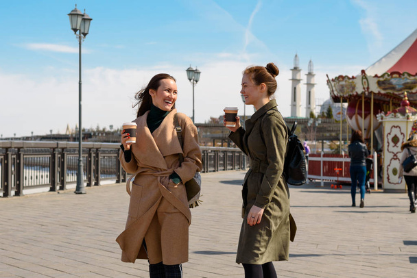 Δύο μελαχρινή κορίτσια σε ένα παλτό και καφέ πάει γύρω από την πόλη του Καζάν. - Φωτογραφία, εικόνα