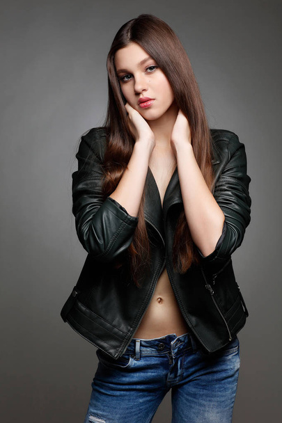 beautiful young woman in leather jacket on grey background, glamour - Fotoğraf, Görsel