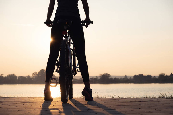 Sziluettje egy lány a bike a tenger közelében. Sport és az aktív élet fogalma - Fotó, kép