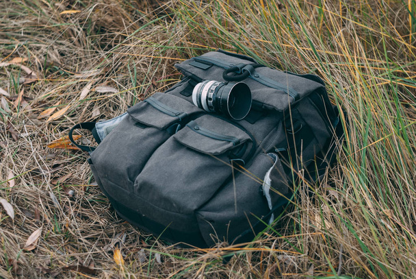 the lens lies on a backpack in the green grass - Photo, Image