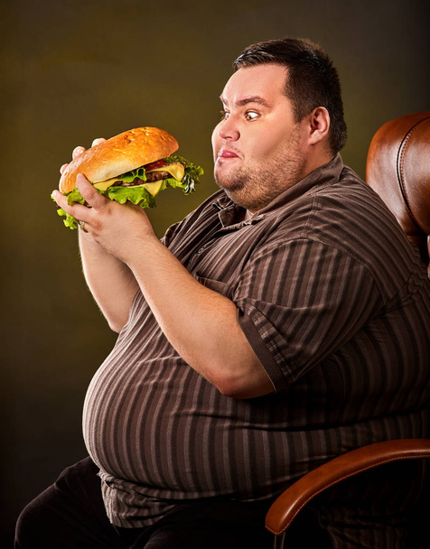 Fat man eating fast food hamberger. Breakfast for overweight person. - Foto, Imagen