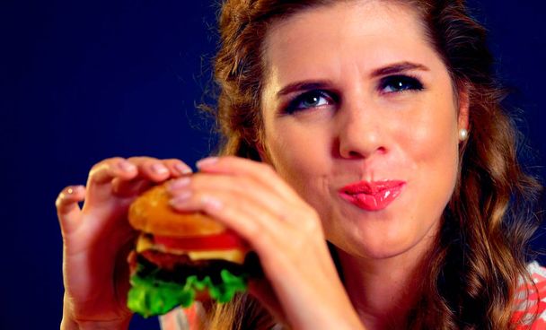 Chica abrió la boca, sosteniendo una hamburguesa en sus manos extendidas y cerró los ojos
. - Foto, imagen